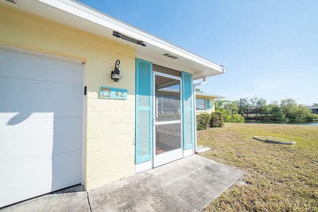 doorway to property featuring a water view and a yard