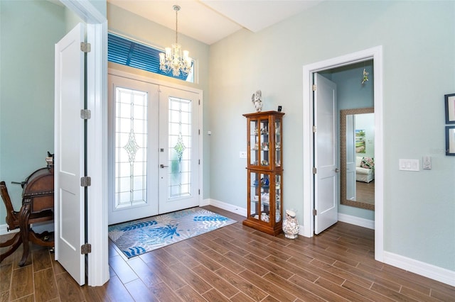 foyer with french doors, dark wood-type flooring, and a notable chandelier