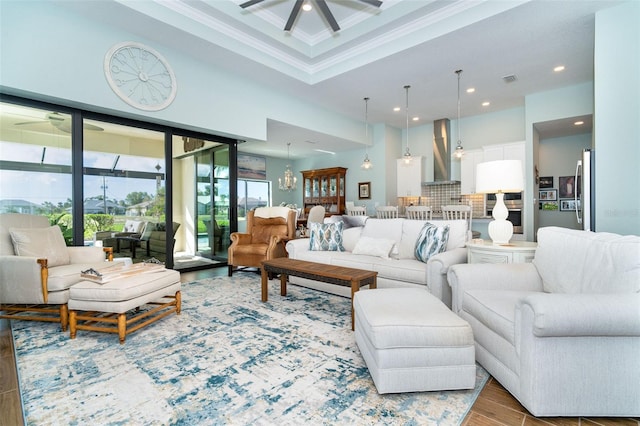 living room featuring wood-type flooring, ceiling fan with notable chandelier, and crown molding