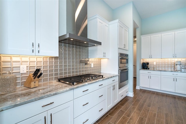 kitchen with white cabinetry, stainless steel appliances, wall chimney range hood, dark hardwood / wood-style flooring, and decorative backsplash