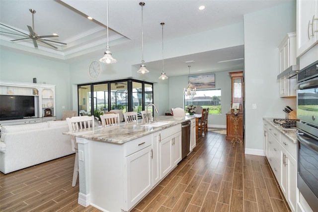 kitchen with white cabinetry, sink, pendant lighting, a breakfast bar, and an island with sink