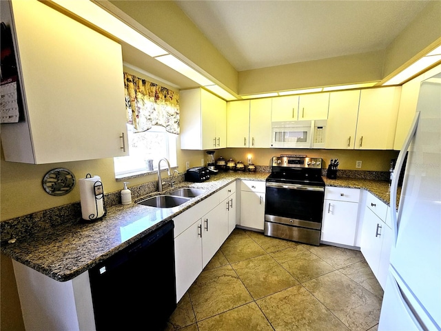 kitchen featuring dark stone counters, white appliances, sink, light tile patterned floors, and white cabinets