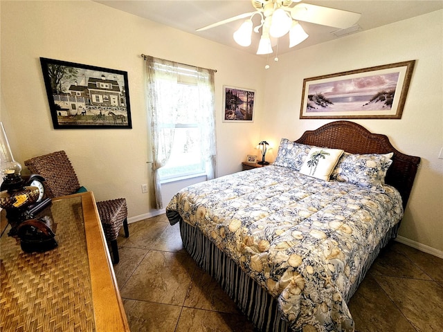 bedroom with dark tile patterned floors and ceiling fan