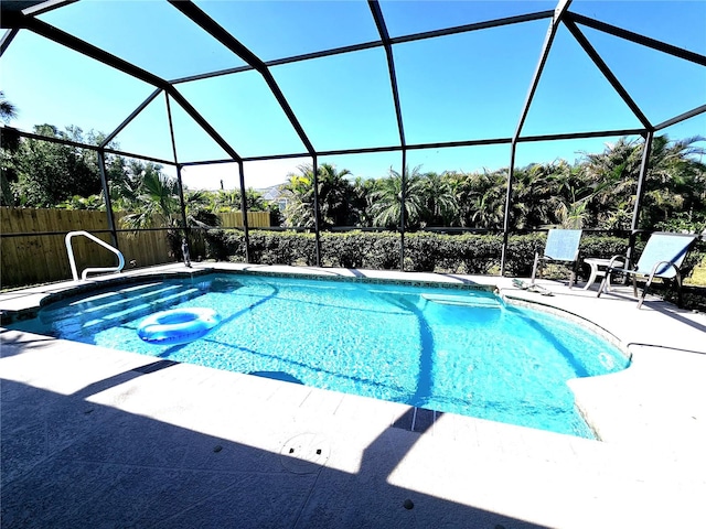 view of swimming pool with glass enclosure and a patio