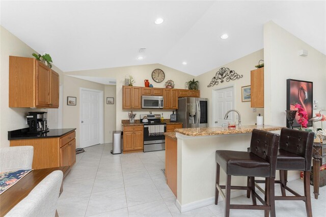 13515 Keystone Blvd, Port Charlotte, FL 33981 - kitchen featuring stainless steel appliances, lofted ceiling, a peninsula, a breakfast bar, and brown cabinets
