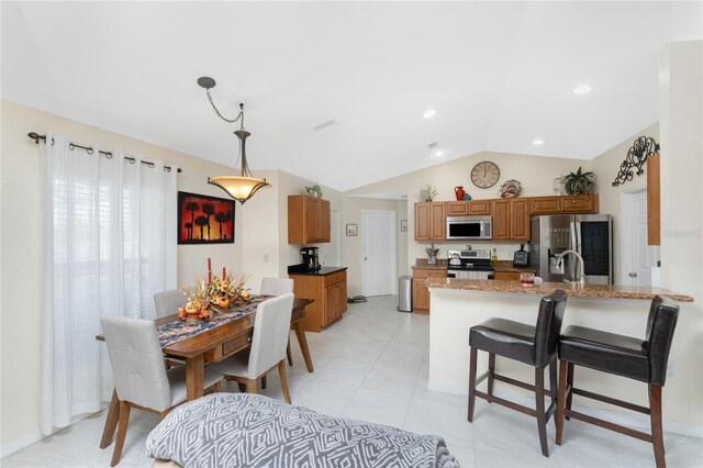 13515 Keystone Blvd, Port Charlotte, FL 33981 - kitchen with appliances with stainless steel finishes, lofted ceiling, brown cabinetry, a peninsula, and hanging light fixtures