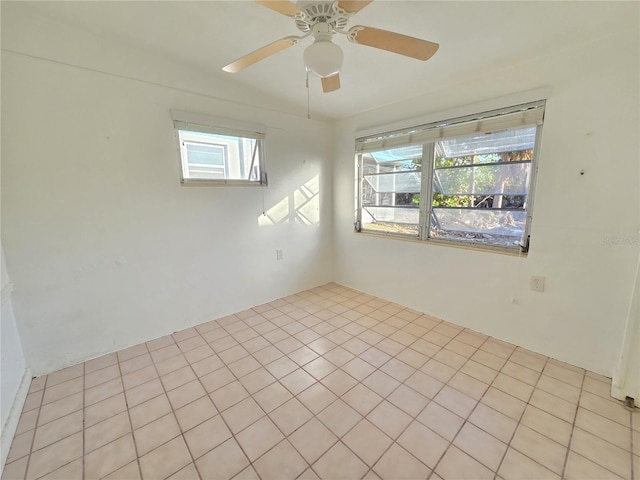 spare room featuring a wealth of natural light, ceiling fan, and light tile patterned floors