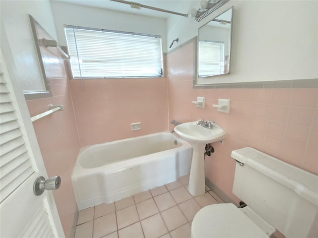 bathroom featuring tile patterned floors, toilet, tile walls, and tiled shower / bath