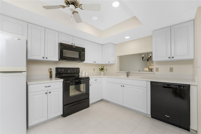 kitchen with a tray ceiling, ceiling fan, sink, black appliances, and white cabinets