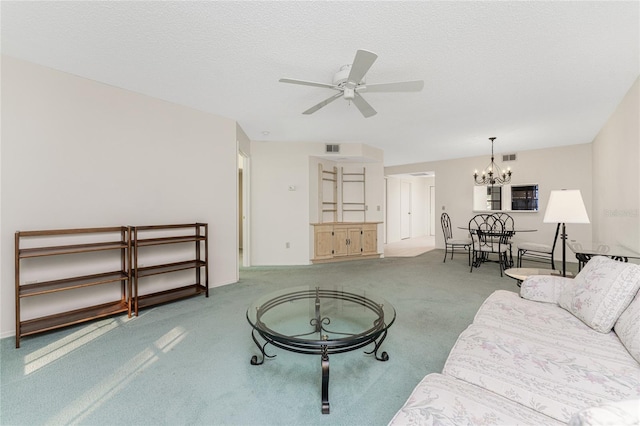 living room featuring ceiling fan with notable chandelier, carpet, and a textured ceiling