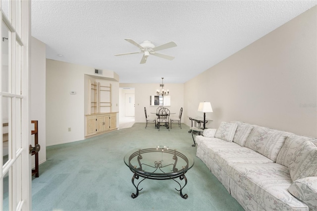 carpeted living room featuring ceiling fan with notable chandelier and a textured ceiling