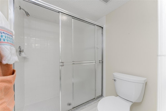 bathroom with a textured ceiling, toilet, and walk in shower