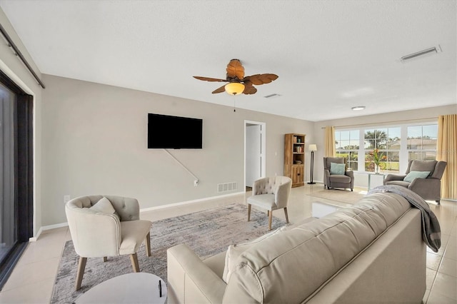 tiled living room with ceiling fan and a textured ceiling