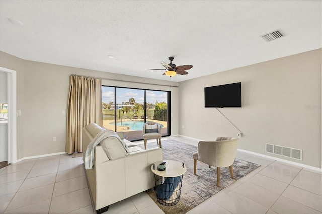 tiled living room with ceiling fan and a textured ceiling