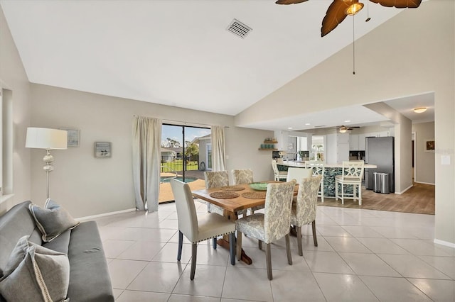 tiled dining space with ceiling fan and high vaulted ceiling