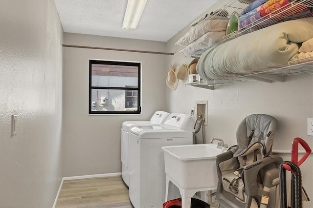 clothes washing area featuring independent washer and dryer, sink, and light wood-type flooring