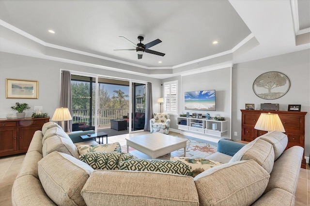 living room featuring a tray ceiling, ceiling fan, light tile patterned flooring, and ornamental molding