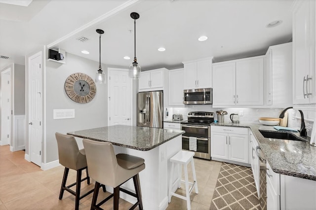 kitchen featuring a center island, dark stone counters, white cabinets, sink, and stainless steel appliances