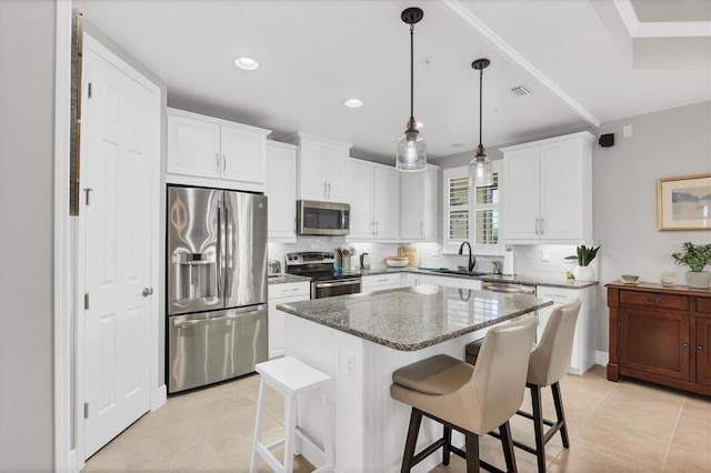 kitchen with appliances with stainless steel finishes, sink, dark stone countertops, a center island, and white cabinetry