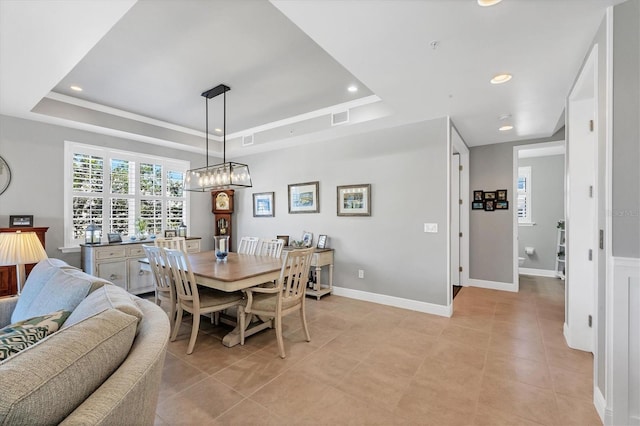 dining area with a tray ceiling and light tile patterned floors