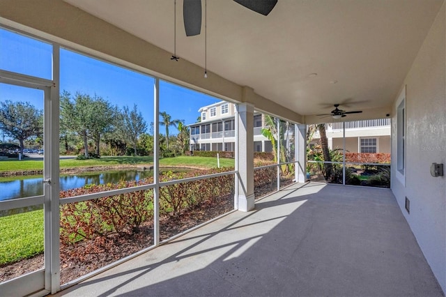 unfurnished sunroom with ceiling fan and a water view