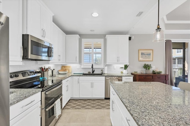 kitchen featuring light stone countertops, appliances with stainless steel finishes, white cabinets, and sink