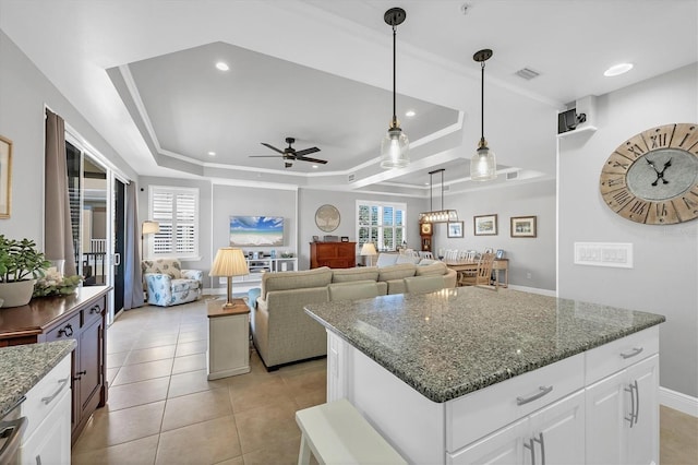 kitchen featuring white cabinets, ceiling fan, a raised ceiling, and dark stone countertops