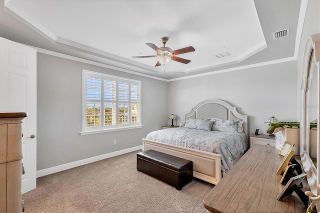 bedroom with ceiling fan, light colored carpet, crown molding, and a tray ceiling