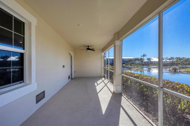 unfurnished sunroom with a water view and ceiling fan