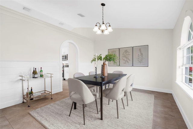 dining area with an inviting chandelier, lofted ceiling, and crown molding