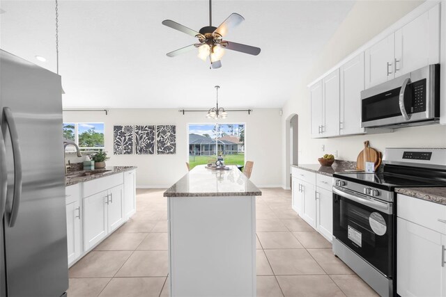 kitchen with a center island, sink, stainless steel appliances, light tile patterned floors, and white cabinets