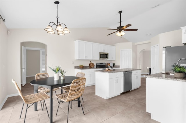 kitchen featuring white cabinetry, light stone counters, vaulted ceiling, a kitchen island, and appliances with stainless steel finishes