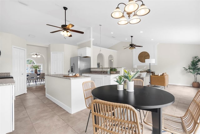 tiled dining room featuring ceiling fan with notable chandelier, lofted ceiling, and sink