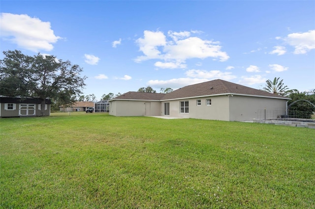 rear view of house featuring a yard and a storage shed