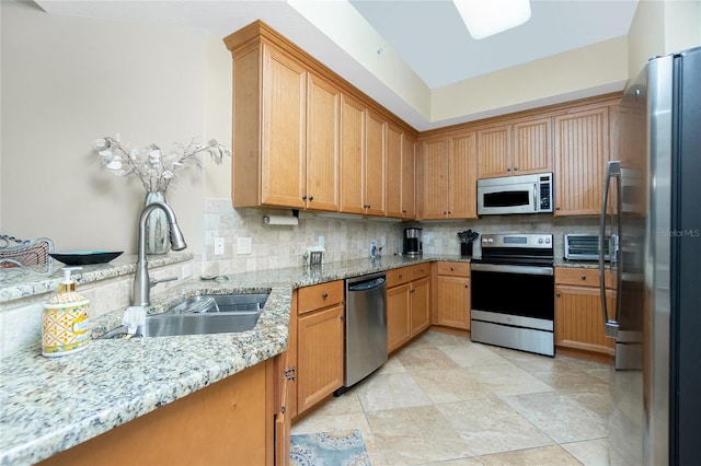 kitchen with decorative backsplash, appliances with stainless steel finishes, light stone counters, and sink