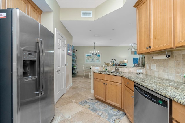 kitchen with backsplash, light stone counters, stainless steel appliances, sink, and an inviting chandelier