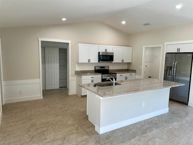 kitchen featuring stainless steel appliances, white cabinets, lofted ceiling, and a kitchen island with sink