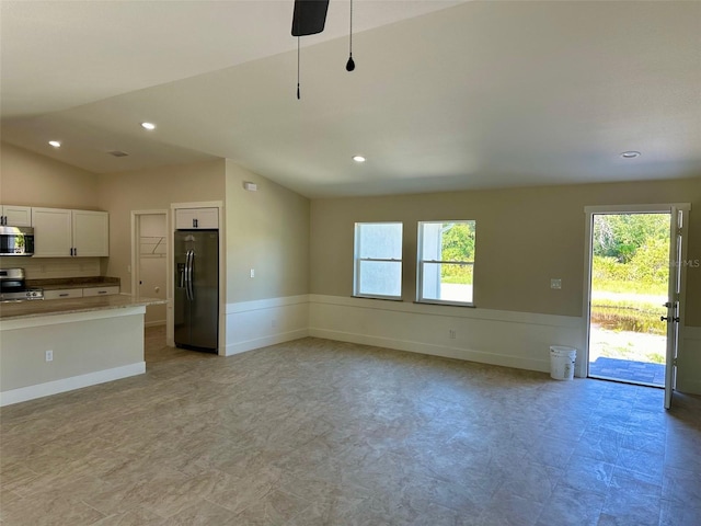 kitchen with vaulted ceiling, pendant lighting, backsplash, white cabinets, and appliances with stainless steel finishes