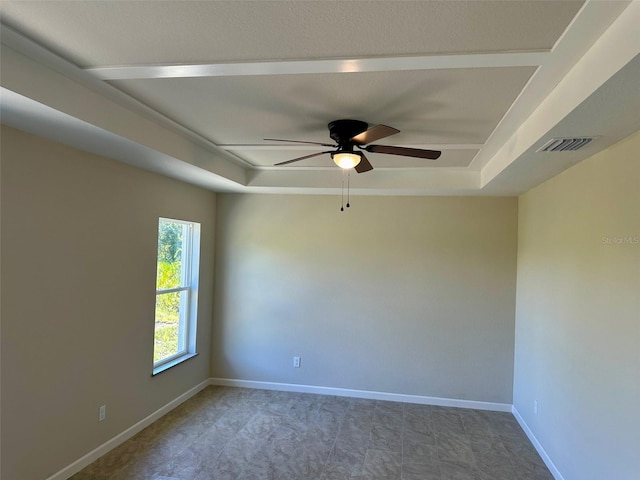 empty room featuring ceiling fan and a tray ceiling