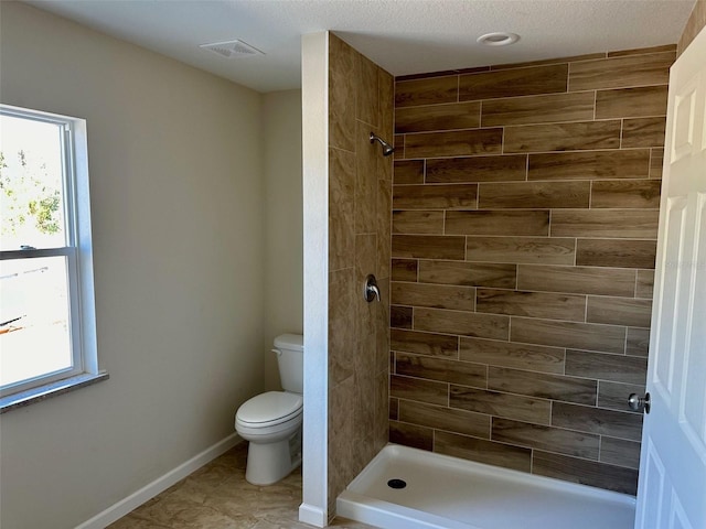 bathroom with tiled shower, tile patterned flooring, and toilet