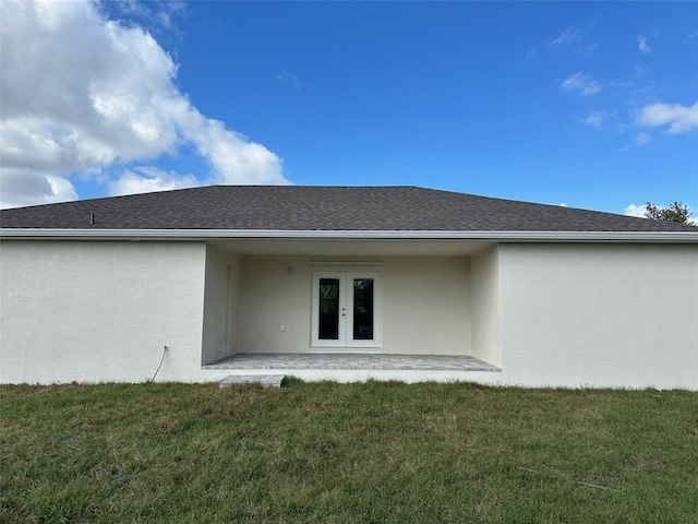 back of property with french doors, a patio, and a lawn