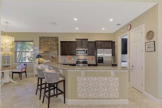 kitchen with a kitchen bar, dark brown cabinets, stainless steel appliances, decorative light fixtures, and a notable chandelier