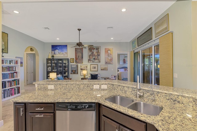 kitchen with dark brown cabinetry, light stone counters, dishwasher, and sink