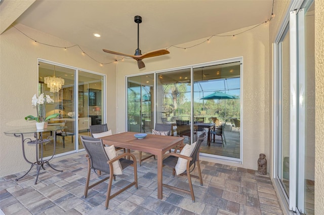 sunroom / solarium featuring ceiling fan with notable chandelier and a wealth of natural light