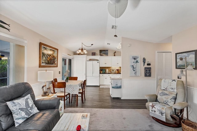 living room with a notable chandelier, dark hardwood / wood-style floors, and vaulted ceiling