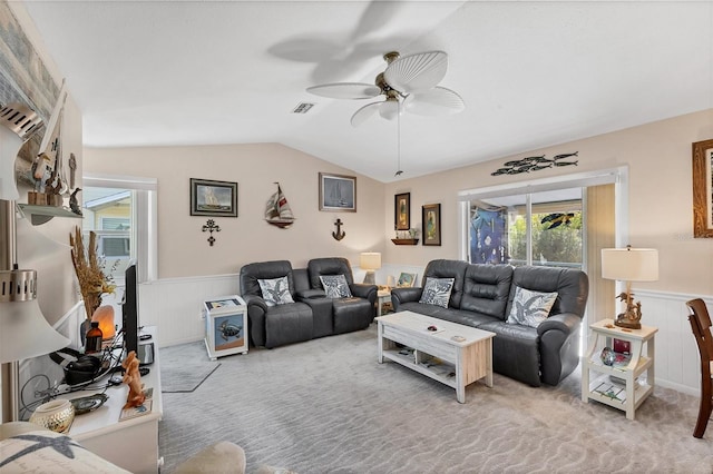 carpeted living room featuring ceiling fan, wood walls, and lofted ceiling