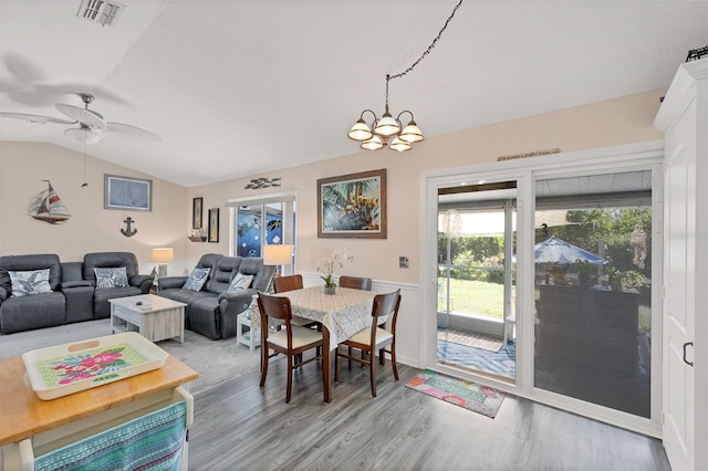 dining area with ceiling fan with notable chandelier, light hardwood / wood-style flooring, and vaulted ceiling