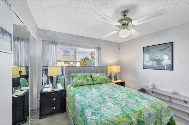 bedroom featuring a textured ceiling, light colored carpet, and ceiling fan