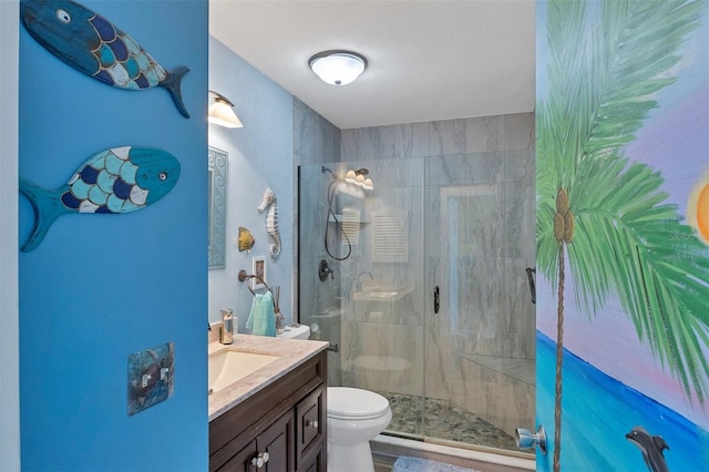 bathroom featuring a textured ceiling, vanity, toilet, and a shower with shower door