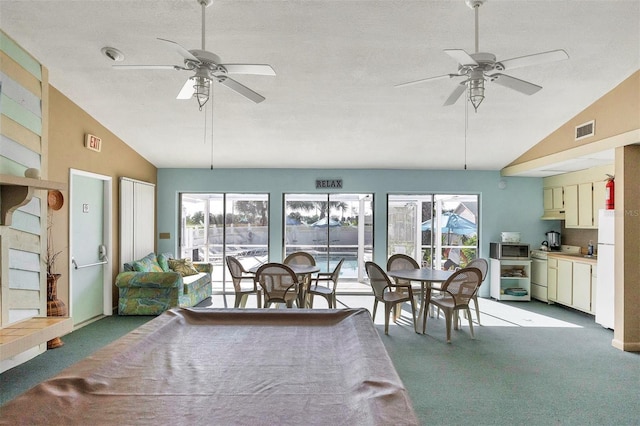 carpeted dining room with vaulted ceiling, plenty of natural light, and ceiling fan